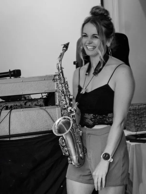 A portrait picture of Alice holding her saxophone and smiling